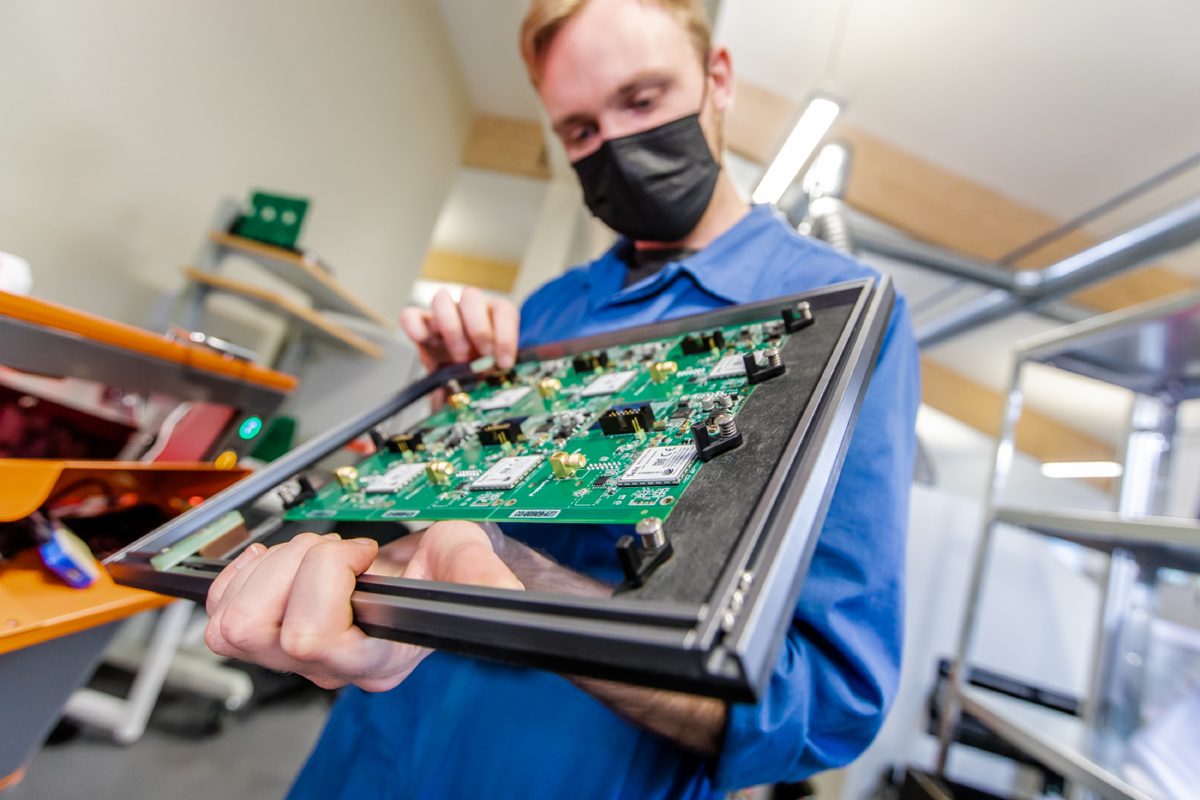 Technician inspecting a prototype PCB assembly in a test fixture